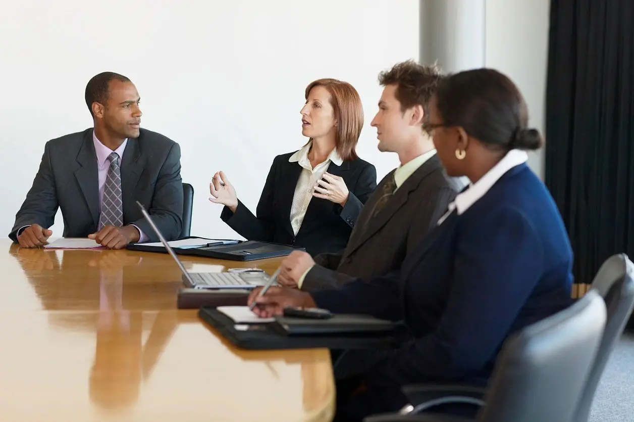 A group of people sitting at a table with laptops.