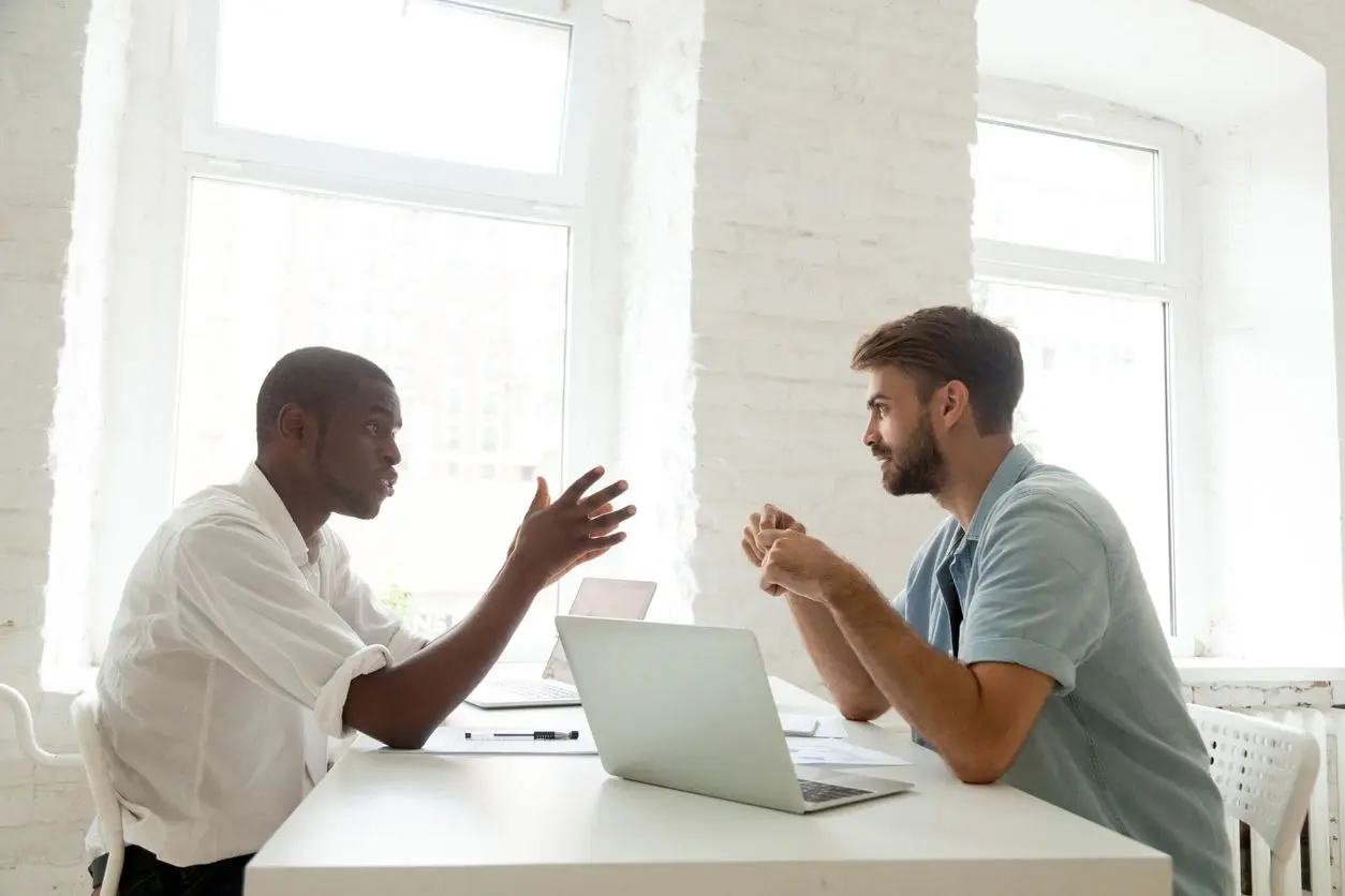 Two men sitting at a table with laptops