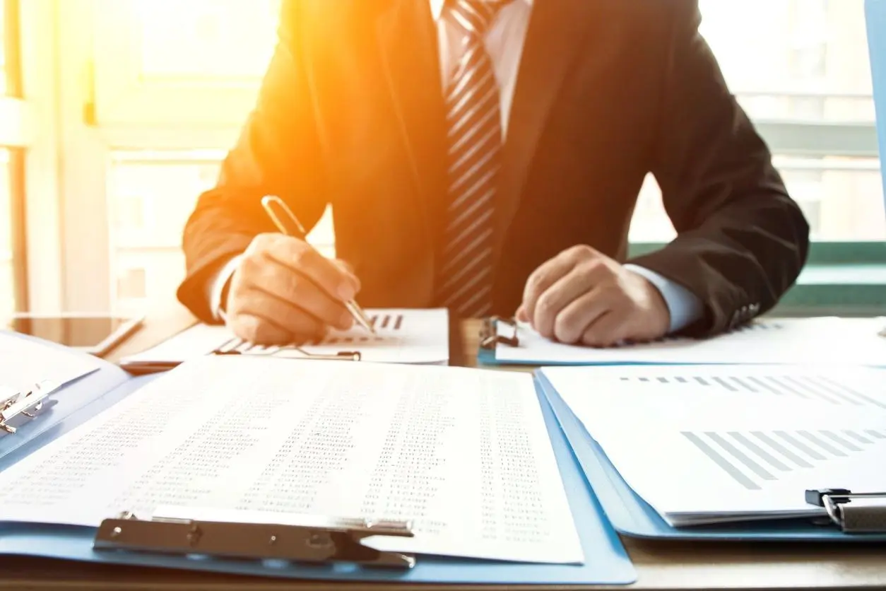 A man in a suit is writing on paper.