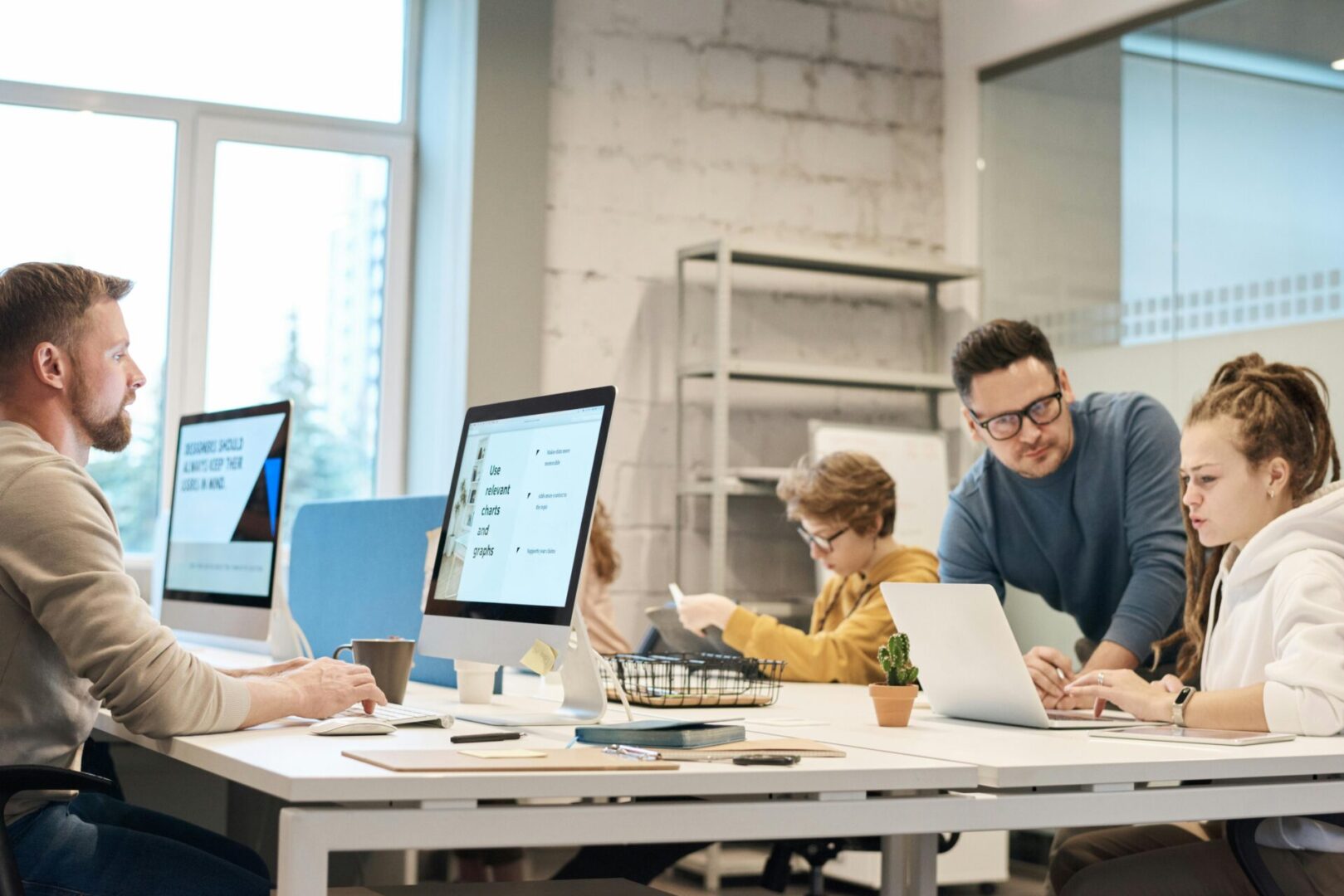 A group of people sitting at tables with laptops.